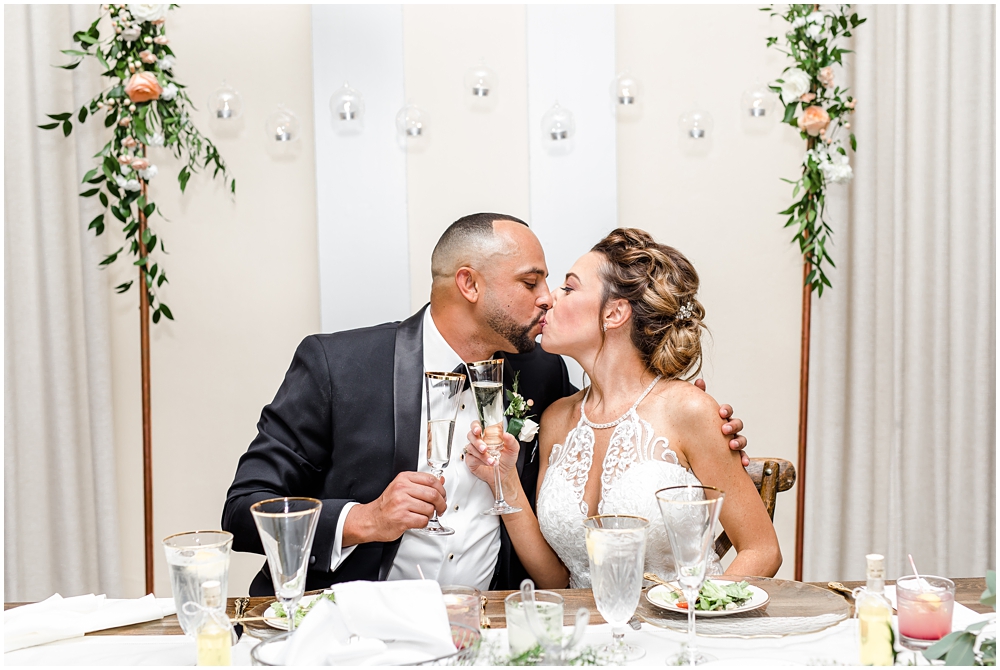 Bride and groom kissing at table with Kate Ryan Event Rentals