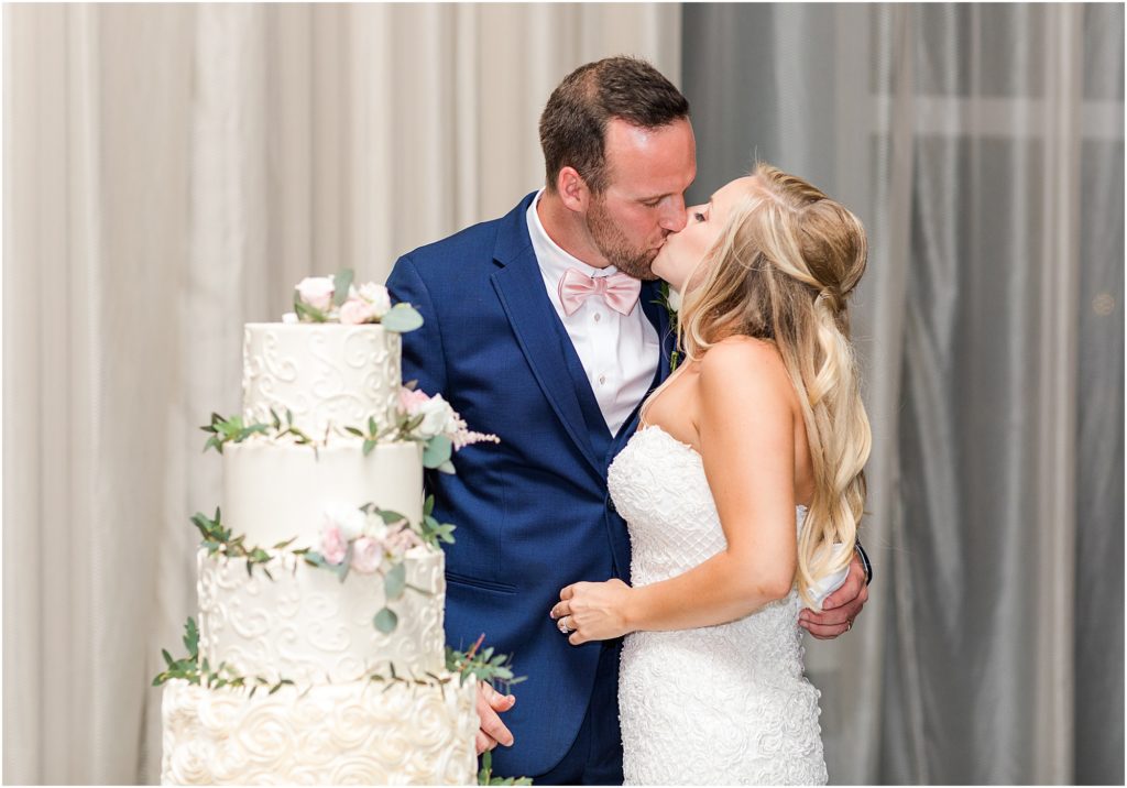bride and groom kissing by the artistic whisk wedding cake at clearwater wedding