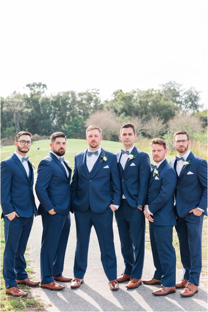 groomsmen in navy blue suits and blue bow ties