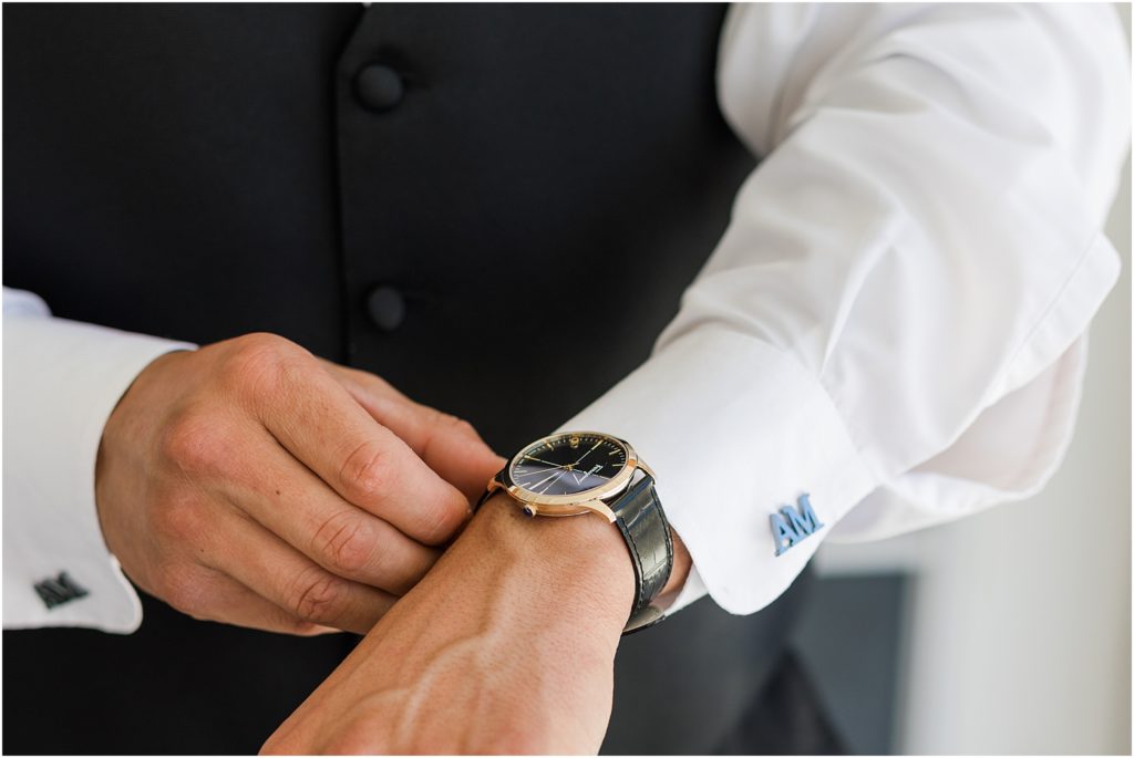 groom putting on blue cuff links with initials 